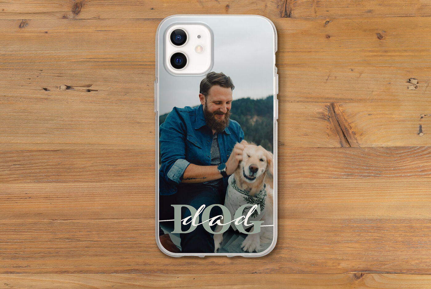 Ein Mann sitzt mit einem Hund auf einer Holzoberfläche und lächelt. Der Hund ist ein Golden Retriever.