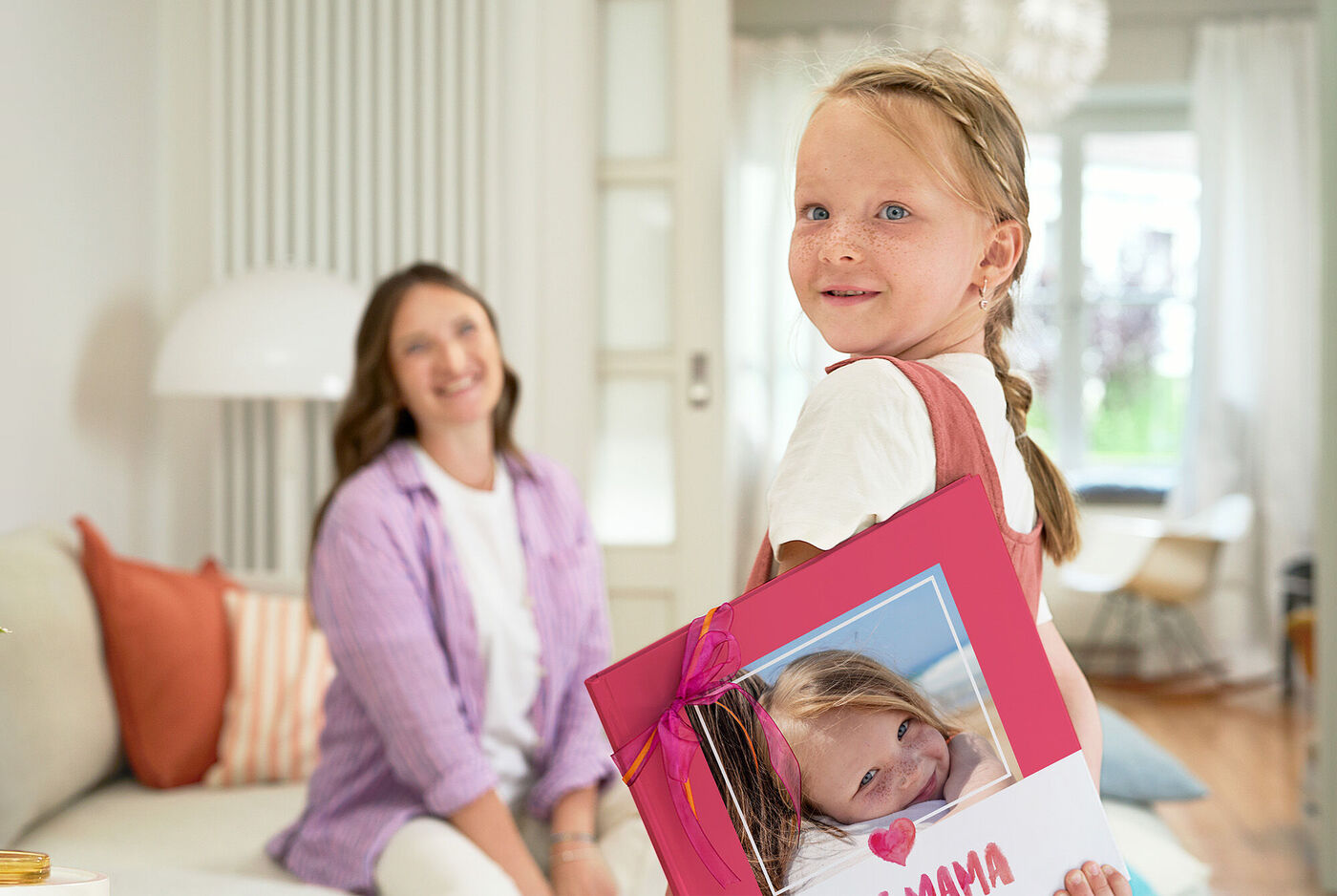 Ein fröhliches Kind zeigt stolz eine persönliche Grußkarte für die Mama.