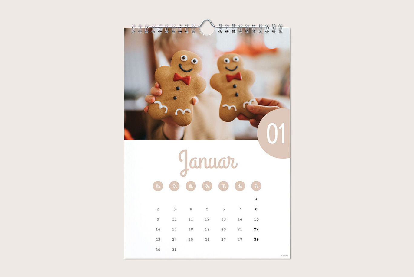 Ein kalenderblatt für Januar mit zwei lachenden Lebkuchenmännern, die von einer Person gehalten werden. Die Monatsansicht zeigt die Tage des Januars klar an.