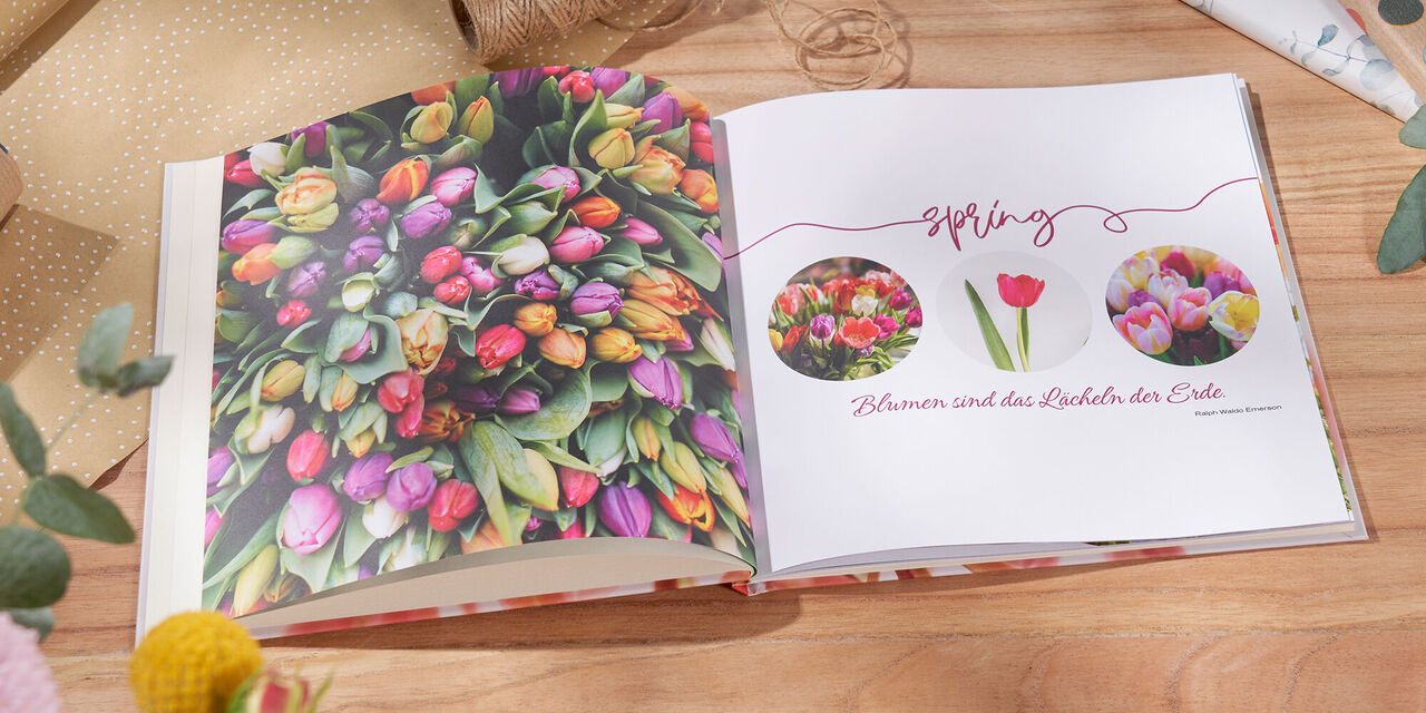 Ein offenes Fotobuch mit bunten Frühlingsblumen und einer liebevollen Botschaft