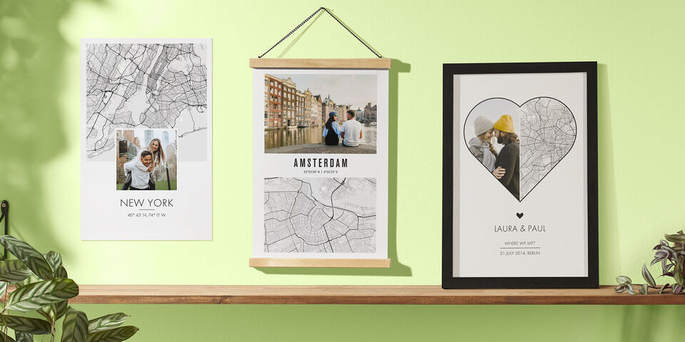 Wandbilder mit Stadtplänen und Fotos auf einer hellgrünen Wand.