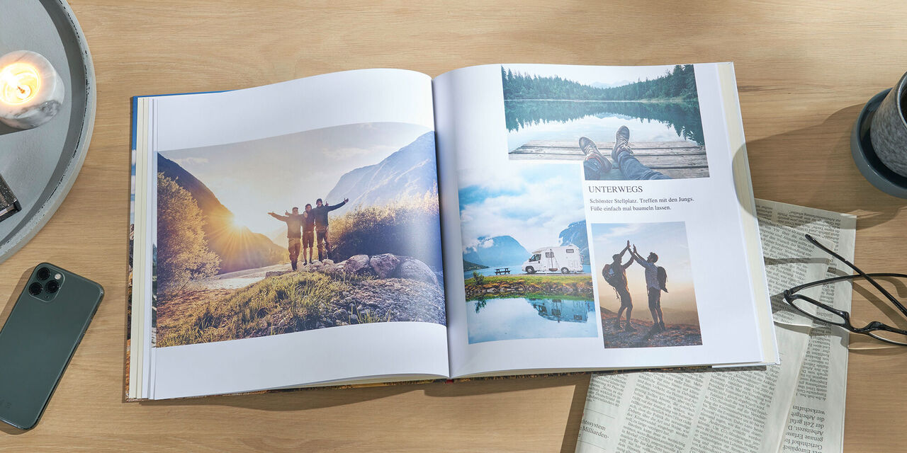 Offenes CEWE Fotobuch auf einem Tisch, mit Fotos von glücklichen Reisemomenten in der Natur und am Wasser