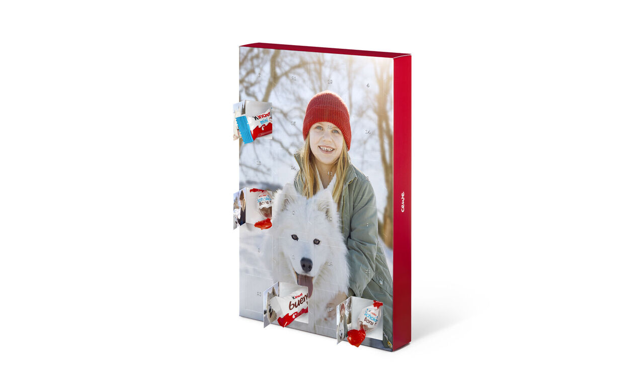 Eine junge Frau mit einem weißen Hund in der Hand. Sie steht in einer verschneiten Landschaft und trägt einen roten Hut. Im Hintergrund befinden sich verschwommene Bäume.