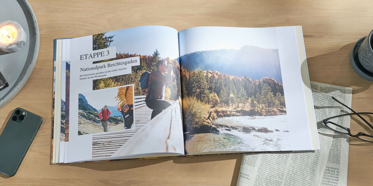 Zwei Personen in einem Fotobuch blättern. Es zeigt Reisen und Natur mit bunten Bildern und Erinnerungen.