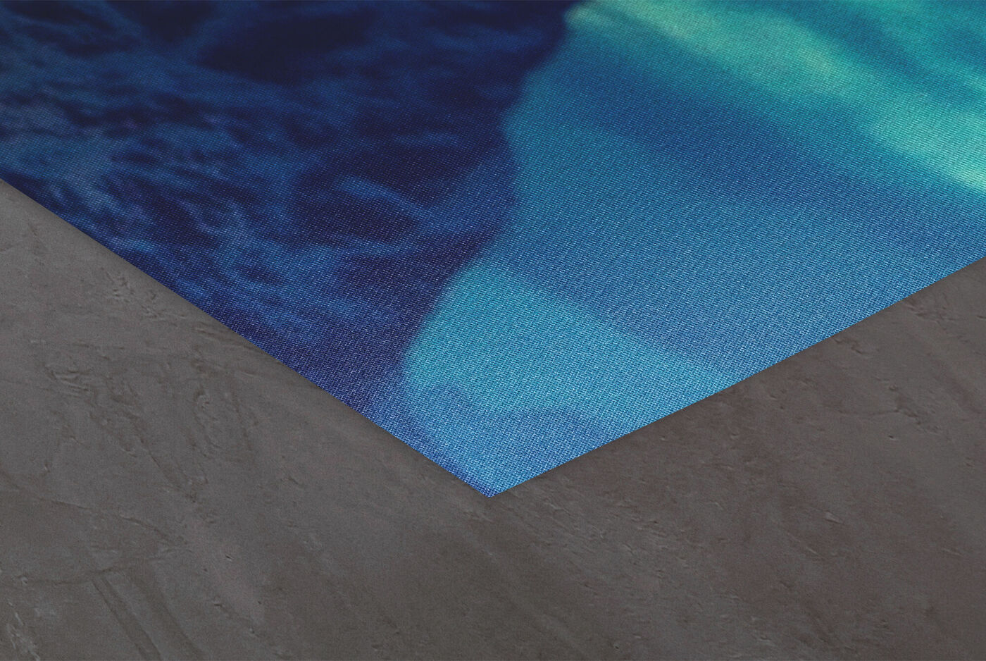 Ecke eines CEWE Posters mit blauem Fotomotiv auf grauem Hintergrund