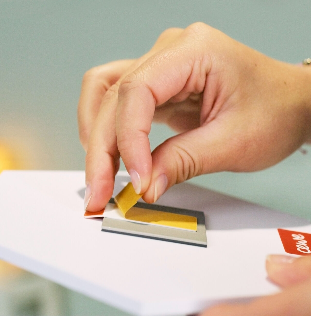Eine Hand klebt ein gelbes Stück Papier auf eine Grußkarte