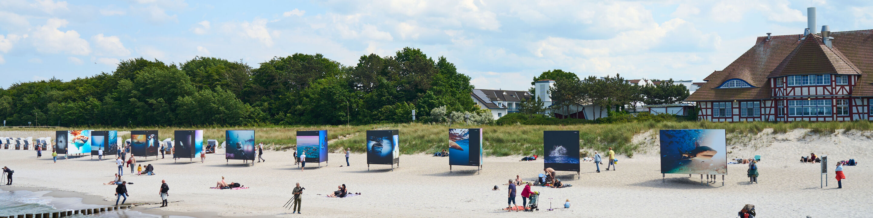 Eine Fotoausstellung entlang eines Strandes.