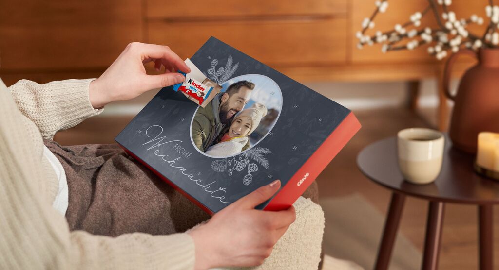 Eine Person hält ein CEWE Fotobuch in den Händen und zeigt darauf. Der Hintergrund ist gemütlich und einladend.