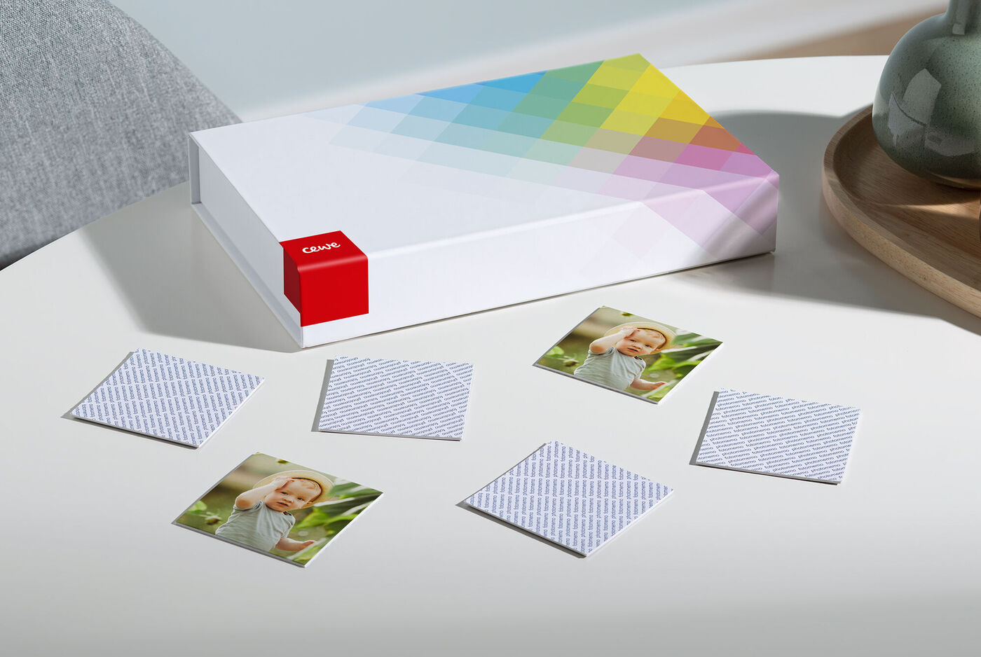 Ein CEWE Fotobuch mit kreativen Fotos auf einem Tisch, umgeben von leeren Karten.