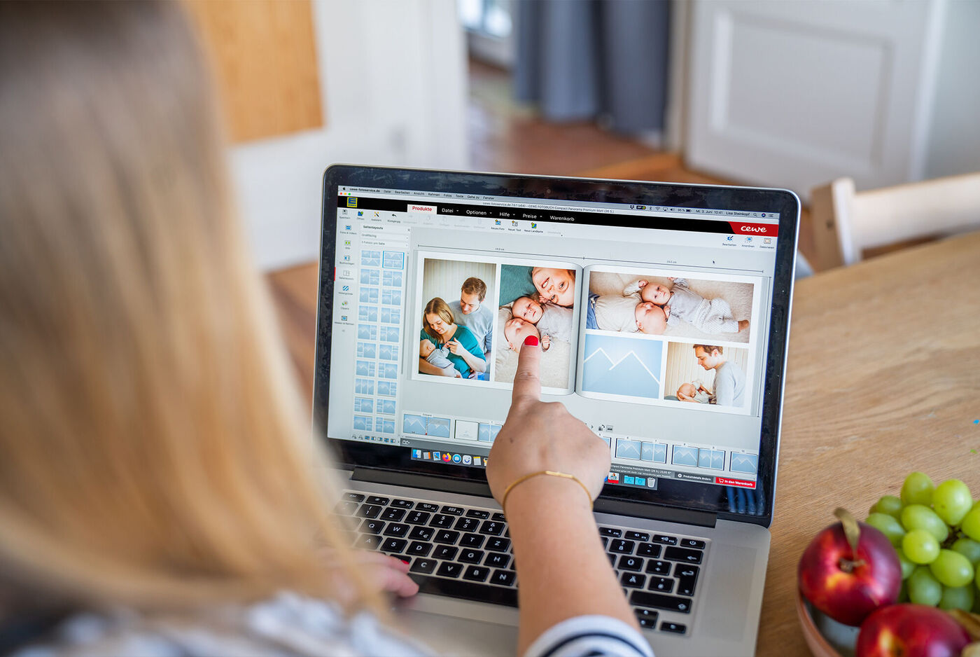 Eine Person arbeitet an einem Laptop und gestaltet ein CEWE Fotobuch.