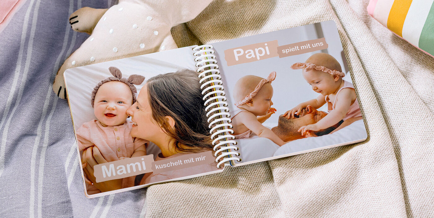 Offenes CEWE FOTOBUCH mit liebevollen Familienmomenten auf einem Tisch