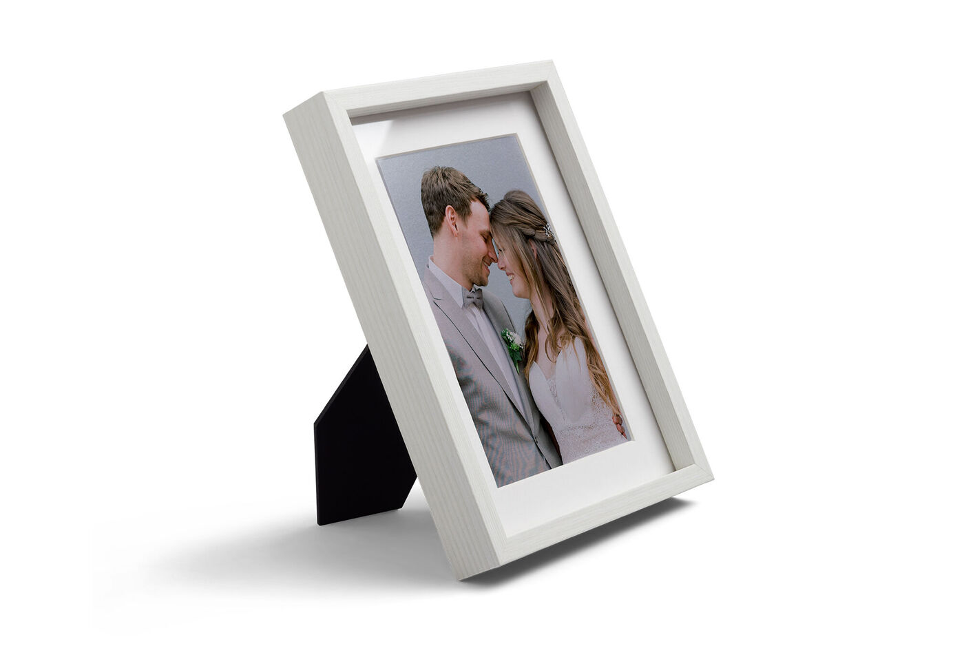 Weißer Rahmen mit Fotoabzug von verliebtem Paar im Hochzeitsoutfit