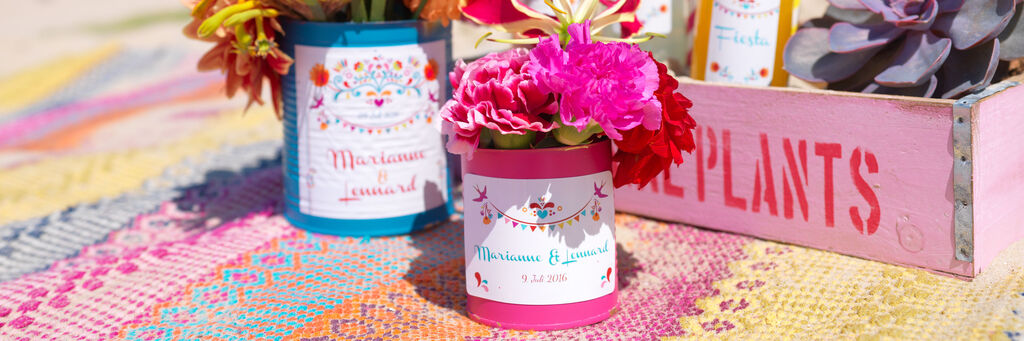 Bunte Blumen in Töpfen, dekoriert mit festlichen Etiketten auf einem bunten Teppich