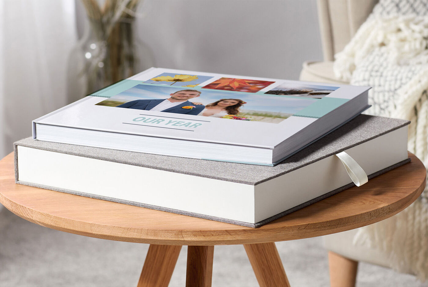 Zwei CEWE FOTOBÜCHER auf einem Tisch. Das eine Buch hat einen Deckel mit Fotos, das andere ist schlicht und dekorativ.