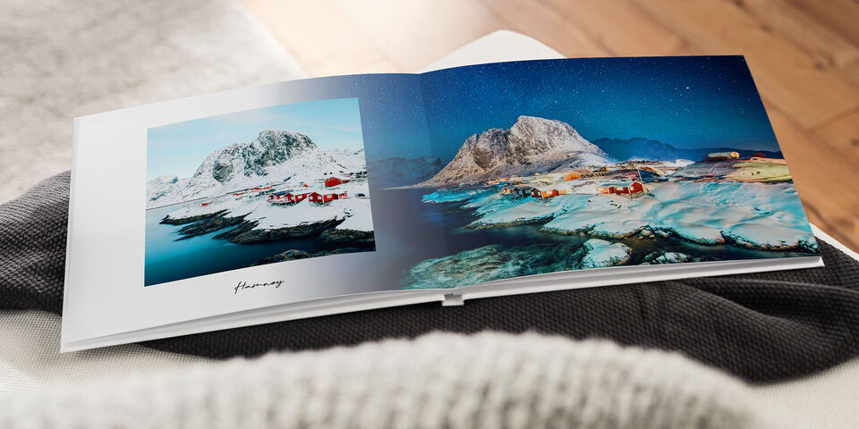 Ein offen liegendes CEWE FOTOBUCH zeigt beeindruckende Landschaftsfotos von Bergen und Fjorden in Norwegen.