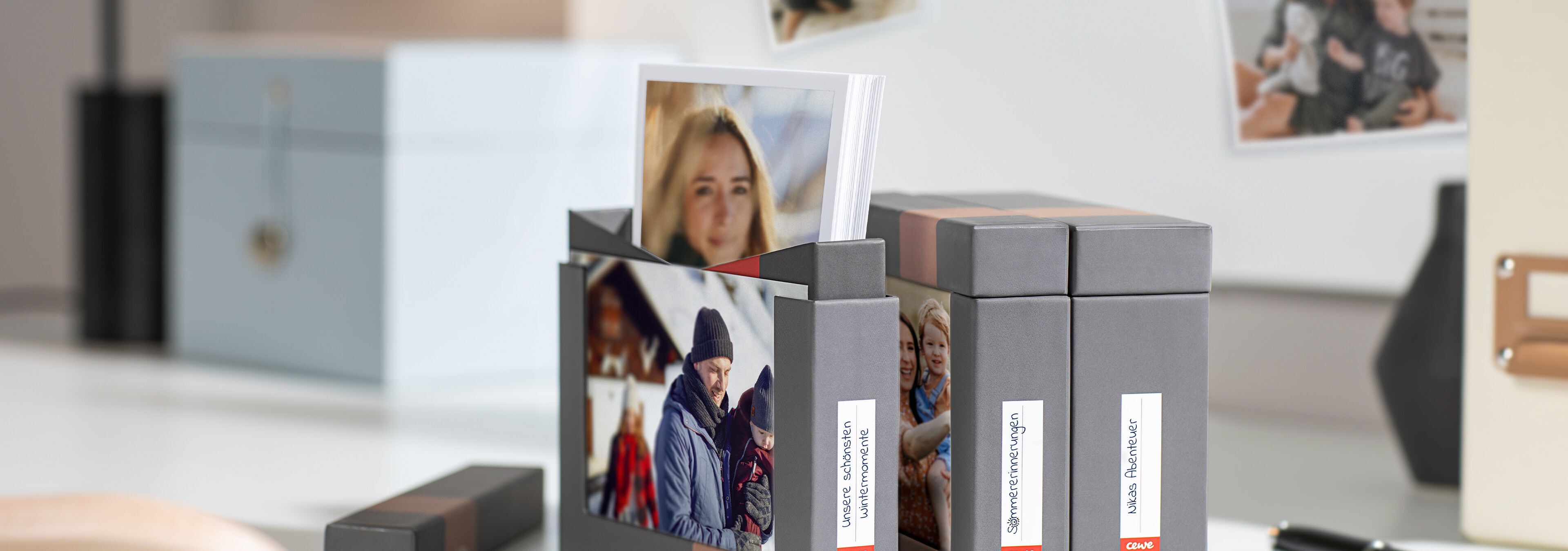 Das Bild zeigt eine stilvolle Box mit persönlichen Fotos. Einige Bilder sind aufgestellt und bereit zum Teilen. Die Box steht auf einem eleganten Tisch, umgeben von weiteren fotografischen Erinnerungen. Eine kreative und liebevolle Präsentation von Erin
