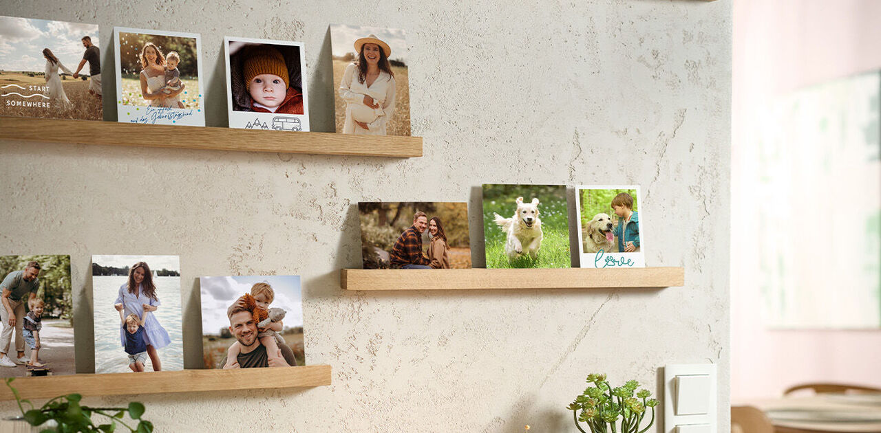 Verschiedene persönliche Fotos stehen auf schlichten Holzleisten dekorativ an einer hellen Wand.