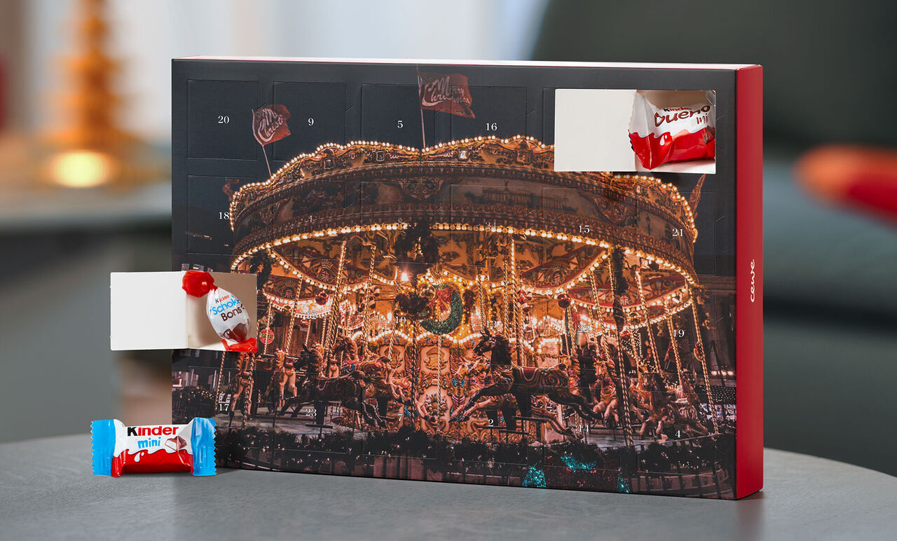 Ein wunderschöner, beleuchteter Adventskalender mit süßen Überraschungen. Darunter sind verschiedene Schokoladen und Süßigkeiten sichtbar, die Freude bereiten. Es ist eine festliche, einladende Stimmung zu sehen.