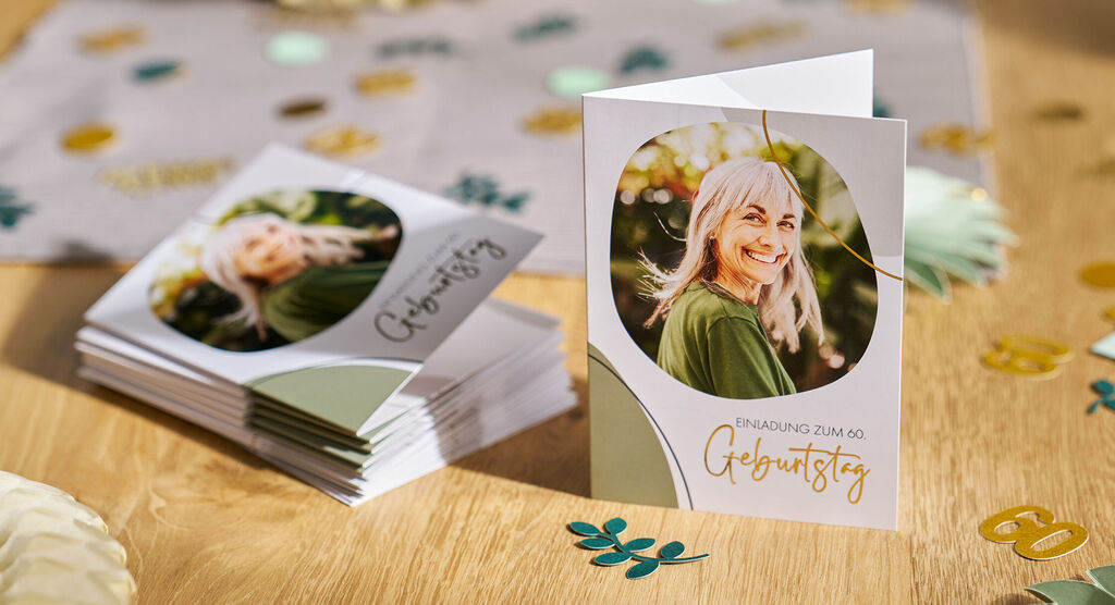 Auf einem feierlich dekorierten Tisch stehen personalisierte Einladungskarten mit grün-goldenen Details.