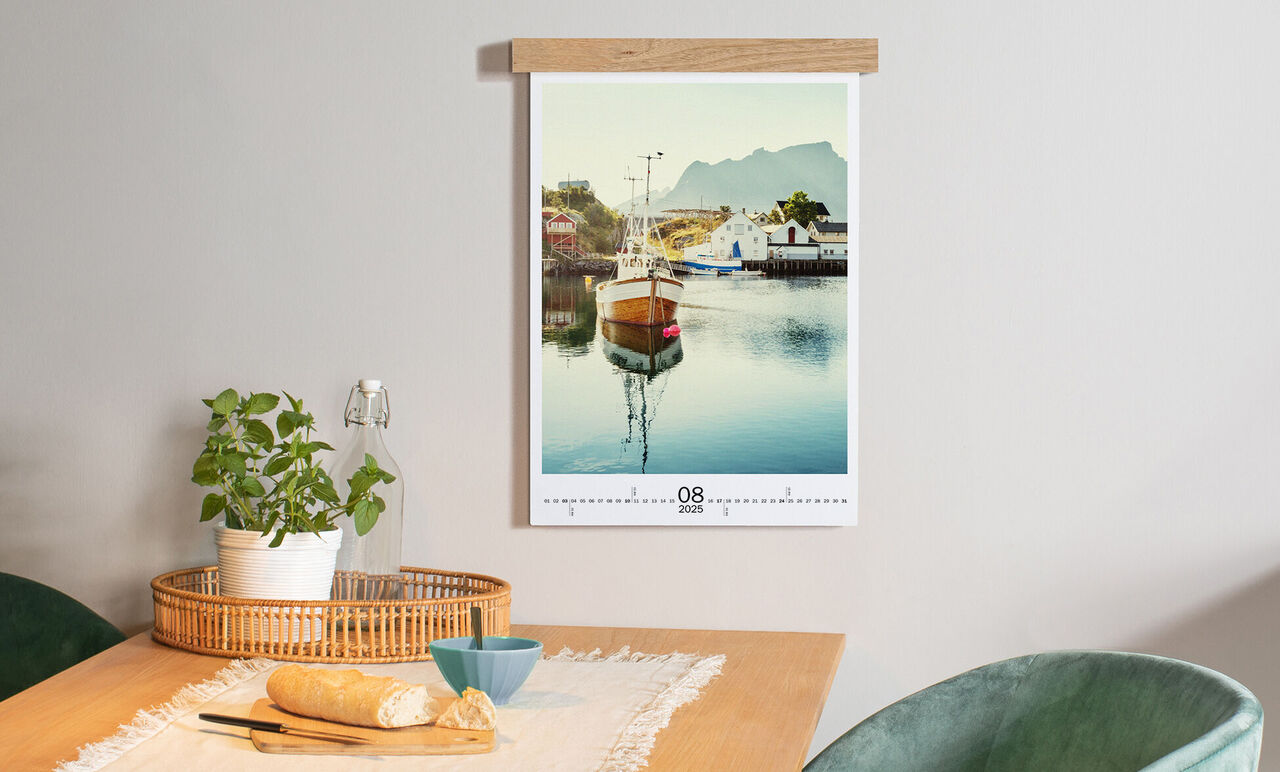 Ein sehenswertes Bild eines Kalenders mit einem Boot auf einem ruhigen Wasser. Der Kalender hängt an der Wand und zeigt den Monat August an.