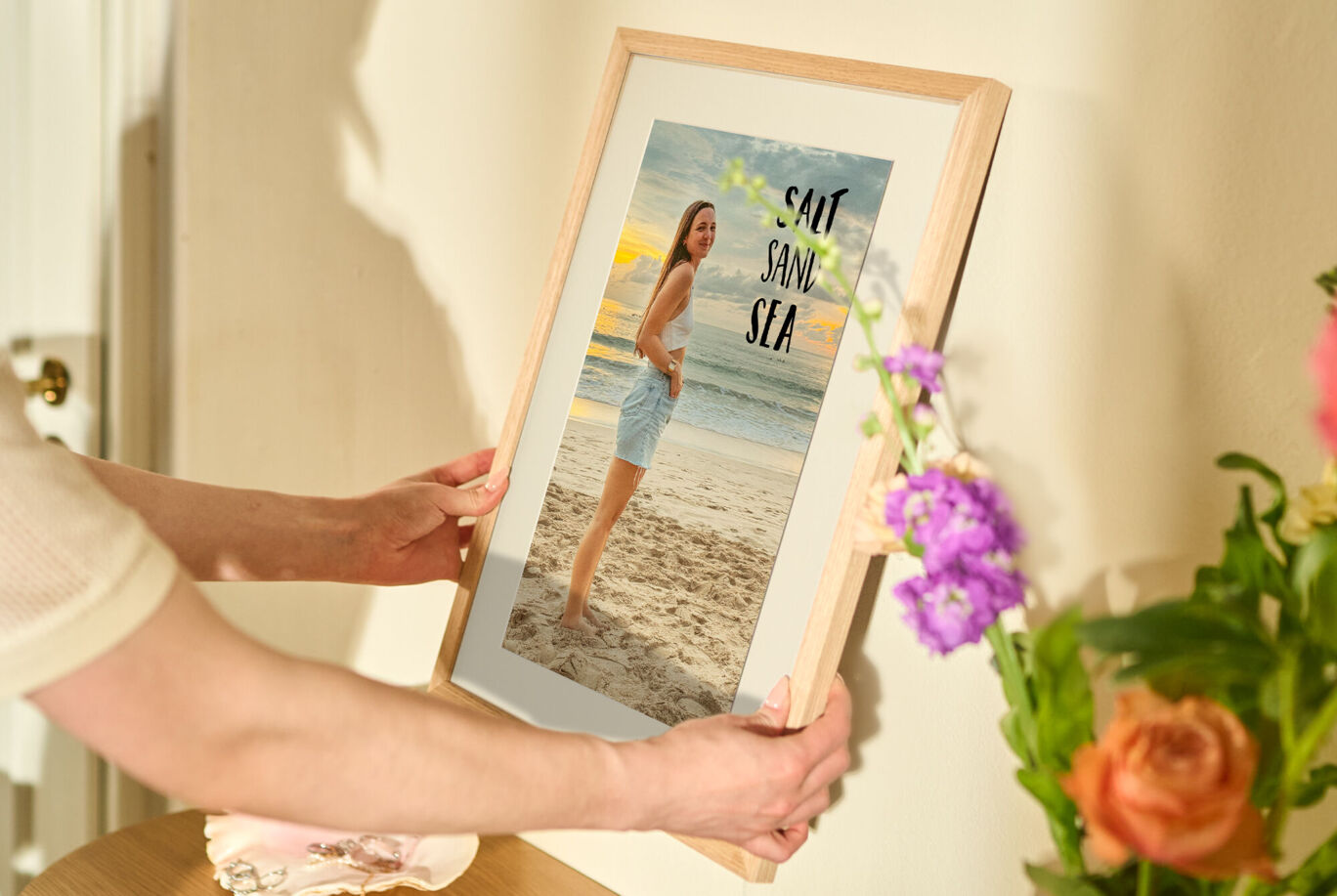 Eine Person hält einen Bilderrahmen mit einem Strandfoto.