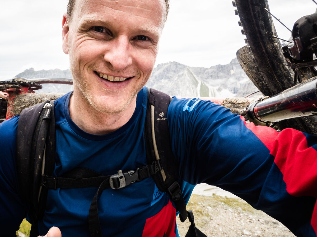 Ein Radfahrer macht ein Selbstporträt vor einer Berglandschaft.