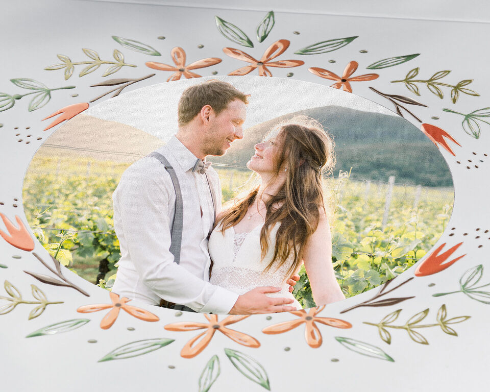 Ein glückliches Paar inmitten von Weinreben, umgeben von floralen Elementen.