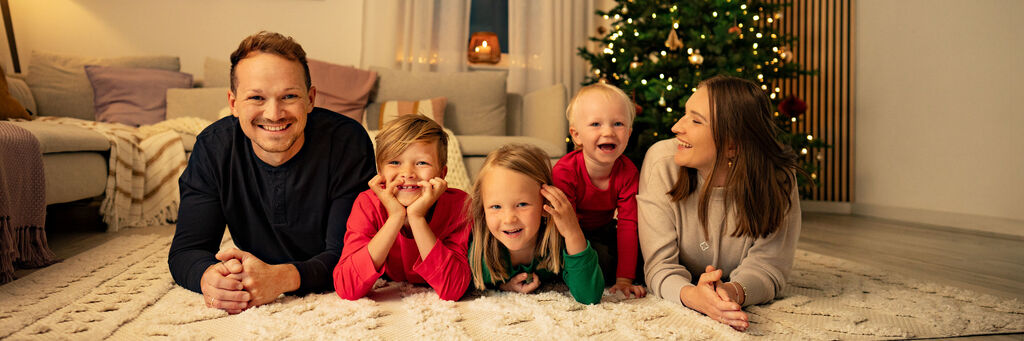 Familie liegt entspannt auf einem Teppich vor dem Weihnachtsbaum, glücklich und vereint.
