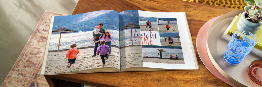 Offenes CEWE FOTOBUCH auf Holztisch mit Familienfotos am Strand und dem Text 'Family Time'