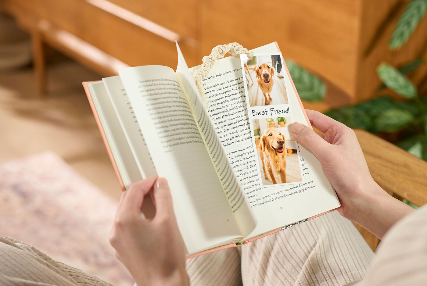 Eine Person liest ein Buch und hält ein Lesezeichen mit einem Bild ihres Hundes in der Hand